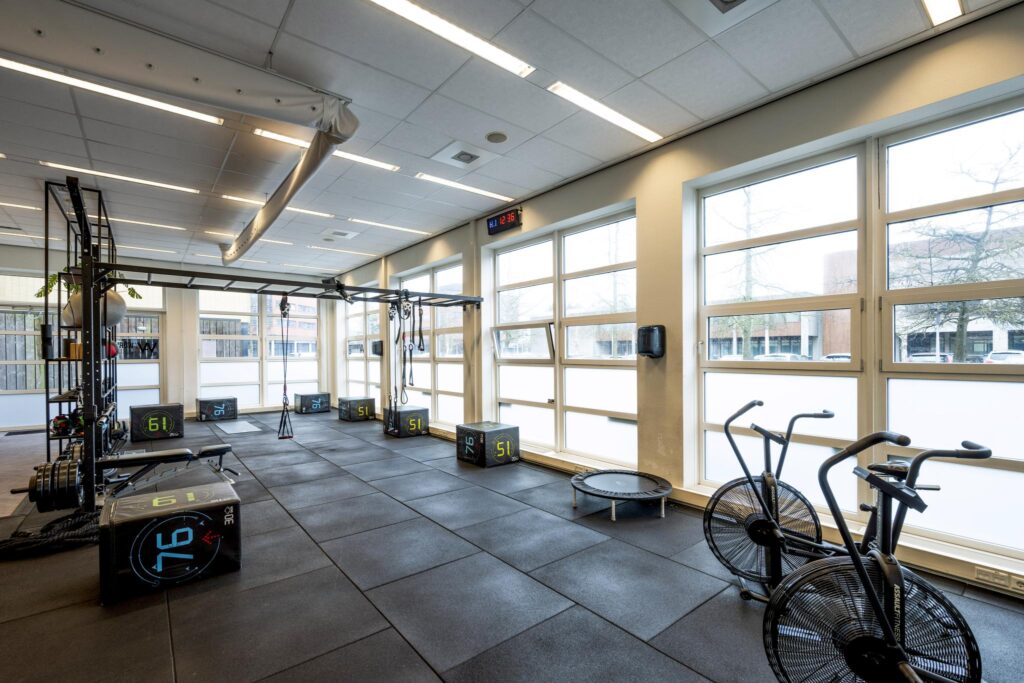 Moderne fitnessruimte aan de H.J.E. Wenckebachweg met trainingstoestellen, plyoboxen en airbikes.